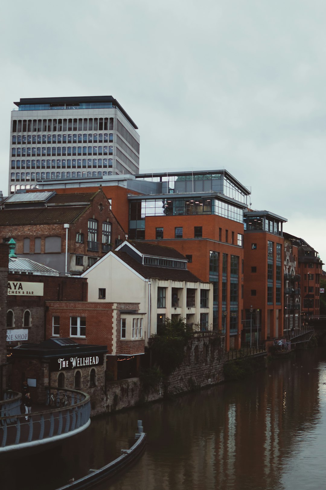 Bristol view on buildings in Castle Park. Rainy day in United Kingdom. Autumn shades in the city. by Community Gardening a river running through a city next to tall buildings