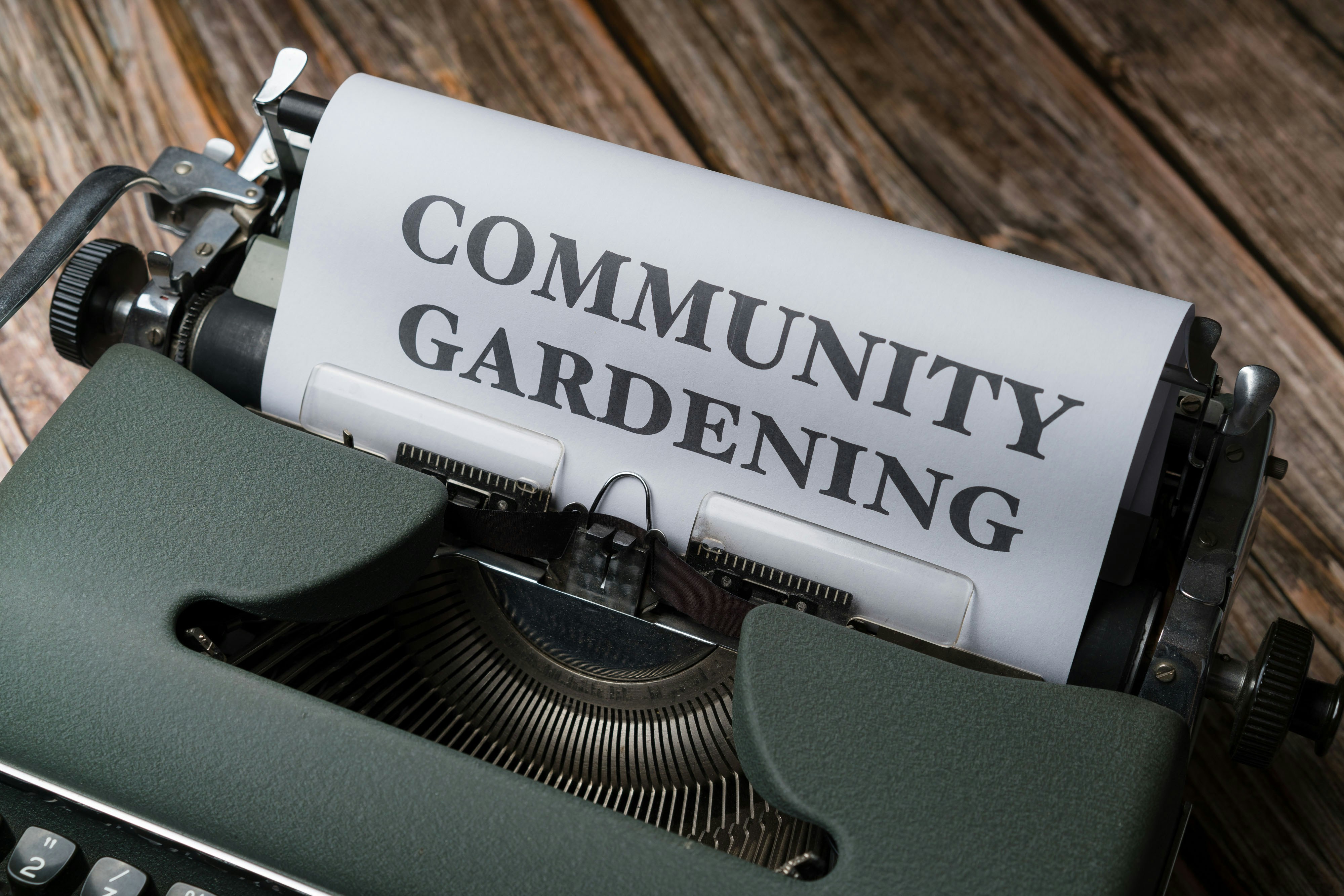 a close up of a typewriter with a paper that reads community gardening